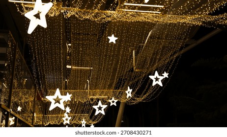 A string of lights with stars hanging from the ceiling. The stars are lit up and the lights are shining brightly. The scene is festive and celebratory, likely for a holiday or special occasion