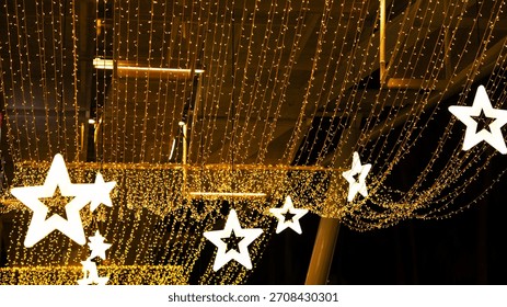 A string of lights with stars hanging from the ceiling. The stars are lit up and the lights are gold