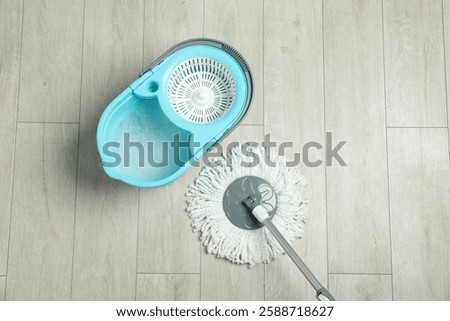 String mop and bucket with detergent on wooden floor, top view