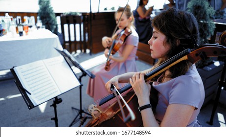 String Quartet In Lilliac Dresses Taking Part In Classical Event Or Wedding Ceremony Outside Summer Terrace