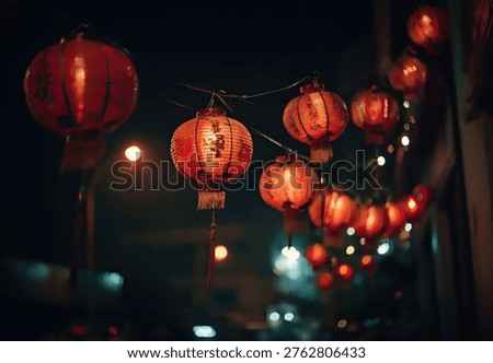 A string of vibrant red Chinese lanterns glows warmly against the dark night sky, illuminating a street scene with soft, festive light.