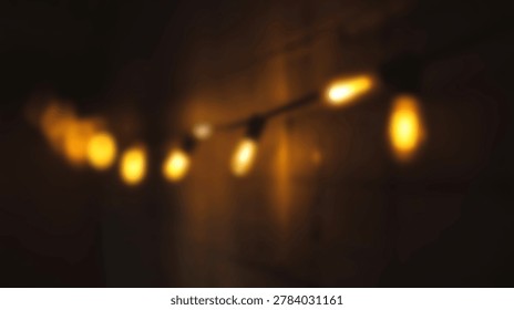 A string of warm glowing Edison style light bulbs is captured in a soft focus blur against a dark background in an indoor setting