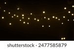 string of white lights hanging from a wire in the dark. The lights are evenly spaced and glow brightly, creating a warm and inviting atmosphere. 