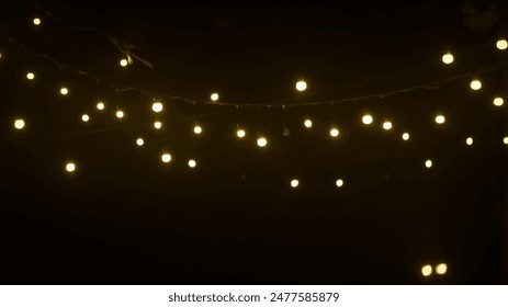 string of white lights hanging from a wire in the dark. The lights are evenly spaced and glow brightly, creating a warm and inviting atmosphere.  - Powered by Shutterstock