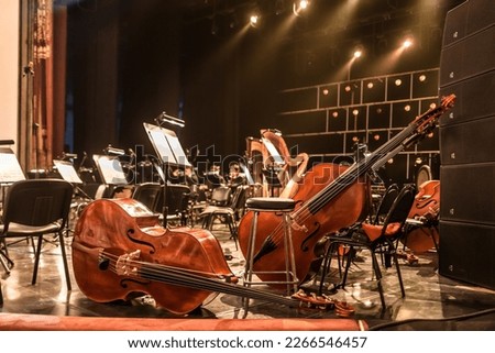 stringed musical instruments of the symphony orchestra lie on the stage before the concert rehearsal. Violins cellos double basses on an empty stage