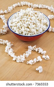 Stringing Popcorn From Above - Bowl Of Popcorn Sits On Butcher Block With Created String And Needle In Piece Of Popcorn