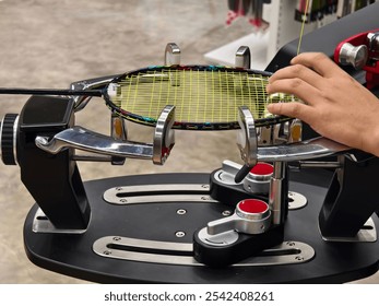 Strings a badminton racket on a racket stringing machine.