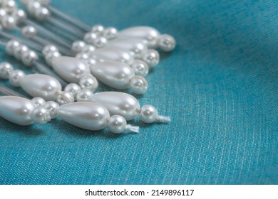 Strings of beaded accents for wedding or formal wear with faux pearl and teardrop beads, draped on a swatch of turquoise satin fabric. Closeup view with shallow depth of field, copy space.