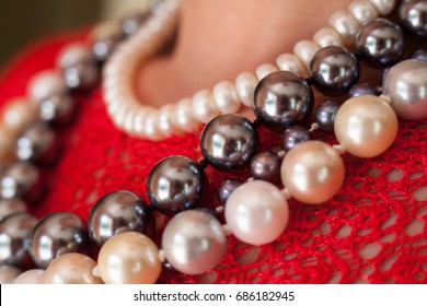 Strings of beads on the red blouse. Close up.
