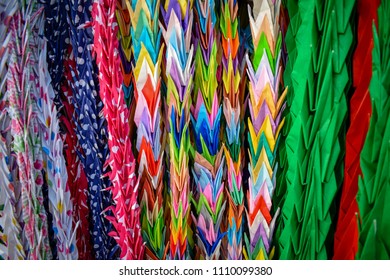 Strings of colourful folded origami paper cranes in Hiroshima peace park, Japan. If you fold a 1000 cranes, you may make a wish.  - Powered by Shutterstock
