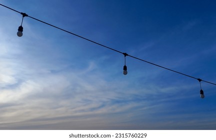 Strings of electric lights and wire under the sky.