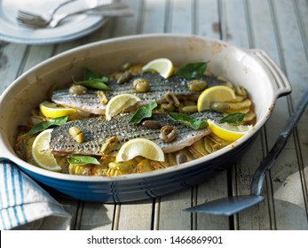 Striped Bass With Potatoes And Olives In A Casserole Dish 