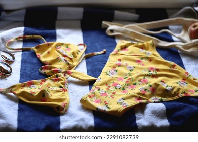 Striped beach towel, floral yellow swimsuit, sunglasses and mesh bag with peaches. Cute beach essentials. Selective focus. - Powered by Shutterstock