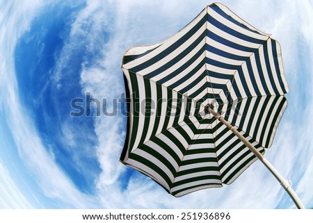 Striped  beach umbrella over blue sky fish eye bottom view
