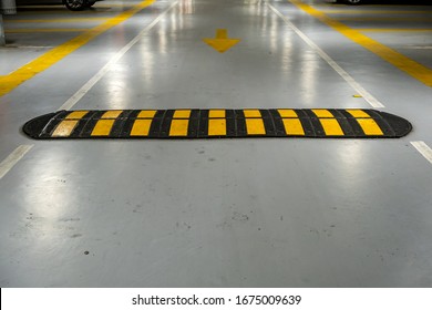 Striped black and yellow speed bump on a road.