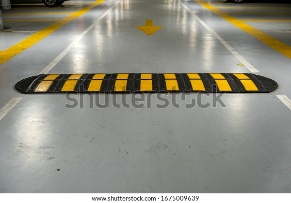 Striped black and\
yellow speed bump on a\
road.