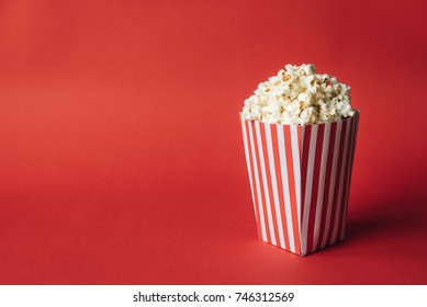 Striped box with popcorn on red background - Shutterstock ID 746312569