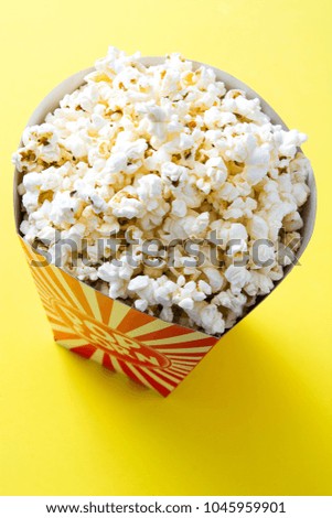 Striped box with popcorn on yellow background.