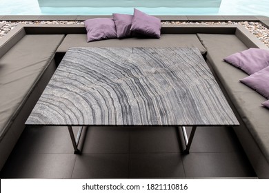 Striped Granite Dining Table With Pillow On Sofa At Side Of Swimming Pool