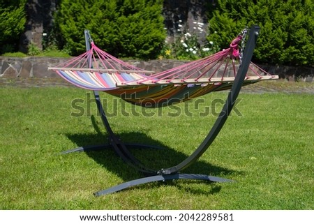 Striped hammock in the backyard. Empty hammock. Backyard multi colored fabric hammock with stand