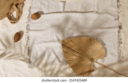 Striped linen beach towel, woven bag and two coconuts on sandy beach with shadows from palm tree. Relaxation and tropical summer holidays concept - Shutterstock ID 2147425489