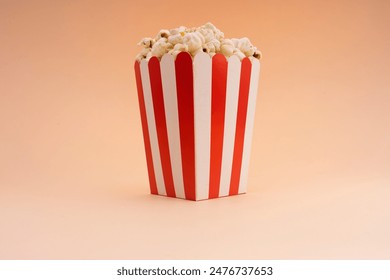 A striped popcorn bucket on a tan background.