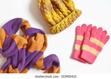 Striped Scarf orange and lilac, yellow hat and pink gloves. Autumn or winter fashion blogger outfit. The combination of bright colors in women's clothes. Flat lay photo, top view