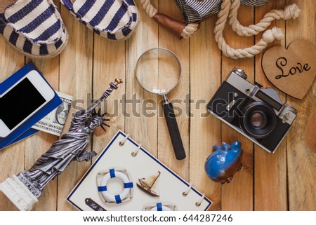 Striped slippers, camera, phone and miniature of the statue of liberty on the wooden background, top view