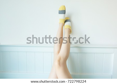 Striped Sock. Woman Slim Legs and Feet Wear Sock Striped on White Wall Background Great For Any Use.