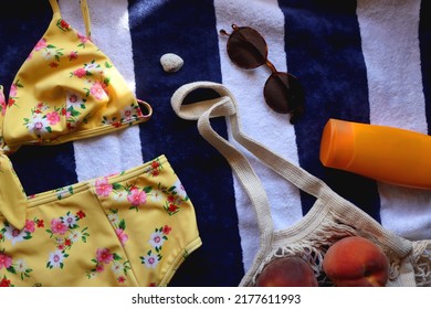 Striped Towel, Yellow Floral Swimming Suit, Sunglasses, Mesh Tote With Fresh Peaches, Seashell And Sunscreen. Beach Essentials, Flat Lay.