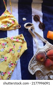 Striped Towel, Yellow Floral Swimming Suit, Sunglasses, Mesh Tote With Fresh Peaches, Seashell And Sunscreen. Beach Essentials, Flat Lay.