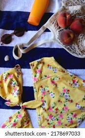 Striped Towel, Yellow Floral Swimming Suit, Sunglasses, Mesh Tote With Fresh Peaches, Seashell And Sunscreen. Beach Essentials, Flat Lay.