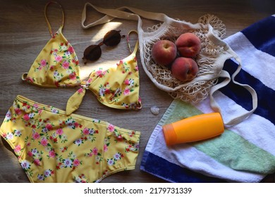 Striped Towel, Yellow Floral Swimming Suit, Sunglasses, Mesh Tote With Fresh Peaches, Seashell And Sunscreen. Beach Essentials, Flat Lay.