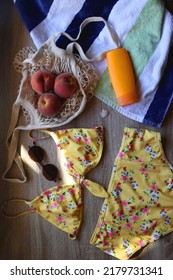 Striped Towel, Yellow Floral Swimming Suit, Sunglasses, Mesh Tote With Fresh Peaches, Seashell And Sunscreen. Beach Essentials, Flat Lay.