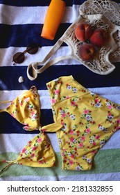 Striped Towel, Yellow Floral Swimming Suit, Sunglasses, Mesh Tote With Fresh Peaches, Seashell And Sunscreen. Beach Essentials, Flat Lay.