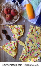 Striped Towel, Yellow Floral Swimming Suit, Sunglasses, Mesh Tote With Fresh Peaches, Seashell And Sunscreen. Beach Essentials, Flat Lay.