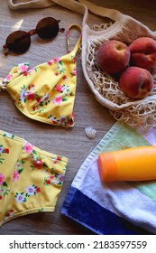 Striped Towel, Yellow Floral Swimming Suit, Sunglasses, Mesh Tote With Fresh Peaches, Seashell And Sunscreen. Beach Essentials, Flat Lay.