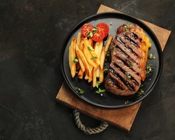 Striploin Beef Steak With French Fries On Dark Background. Freshly Grilled. Healthy Dinner. Mediterranean Diet. Top View, Flat Lay, Copy Space