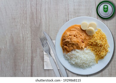 Stroganoff dish with rice, heart of palm and potato sticks, and a soda on a table - top view