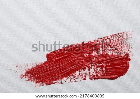 Stroke of red paint on white canvas, top view. Space for text