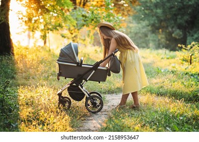 Strollers for Newborns. Keep baby safe in stroller. Mother walking with Newborn baby in stroller in summer park in sunny day