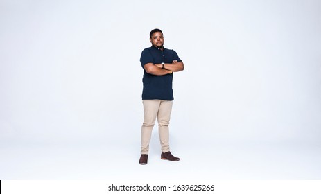 Strong African Man Standing Against White Background. African American Man Looking At Camera Standing With His Arms Crossed.