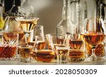 Strong alcohol drinks, hard liquors, spirits and distillates iset in glasses and bottles: cognac, scotch, whiskey and other. Black bar counter background