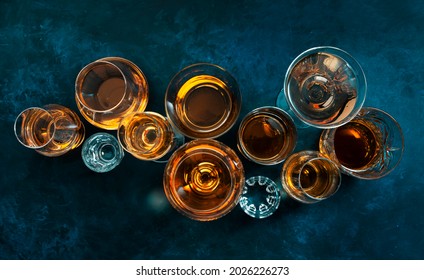 Strong alcohol drinks, hard liquors, spirits and distillates iset in glasses: cognac, scotch, whiskey and other. Blue background, top view  - Shutterstock ID 2026226273
