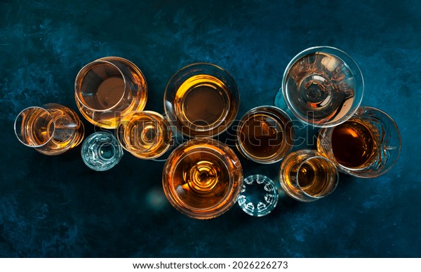 Strong alcohol drinks, hard liquors, spirits and\
distillates iset in glasses: cognac, scotch, whiskey and other.\
Blue background, top view\
