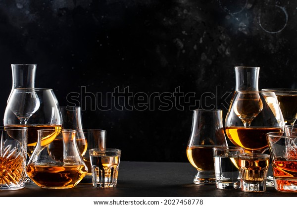 Strong alcohol drinks, hard liquors, spirits
and distillates iset in glasses: cognac, scotch, whiskey and other.
Black bar counter
background