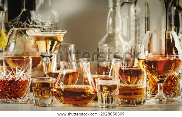 Strong alcohol drinks, hard liquors,\
spirits and distillates iset in glasses and bottles: cognac,\
scotch, whiskey and other. Black bar counter\
background