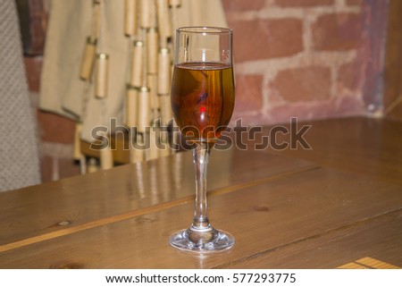 A strong alcoholic drink of dark color in a tall glass.
