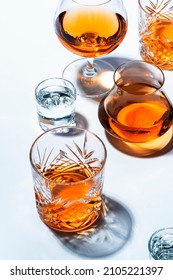 bebidas alcohólicas fuertes, licores duros, licores y destilados en gafas: vodka, cognac, whisky y otros. Fondo blanco. Luz dura, espacio de copia