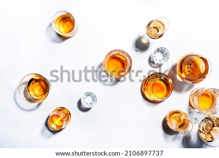 Strong alcoholic drinks, hard liquors, spirits and distillates in glasses: vodka, cognac, whiskey and other. White background. Hard light, copy space